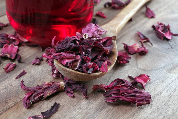 hibiscus tea. dry hibiscus petals in a wooden spoon on a wooden table. herbal vitamin tea. cold and flu remedy. close up.