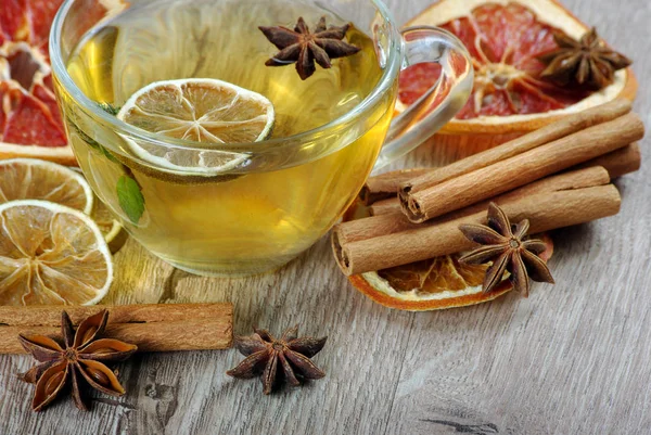honey and tea. cup of herbal tea with lemon, honey, dried citruses, anise stars and cinnamon sticks on a wooden table. hot tea for colds and flu.