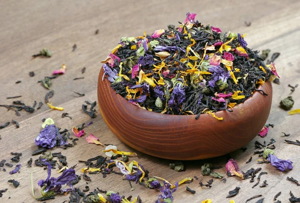 blended tea. black tea with dry flower petals and fruits. blended tea in a bowl on a wooden table. copy spaces
