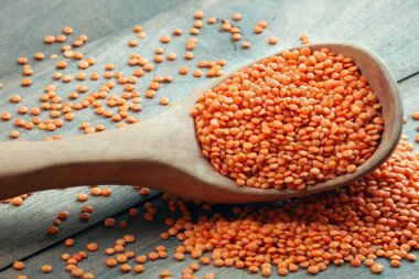 Tahta bir masada, tahta bir kaşıkta kırmızı mercimek. en üstteki görünüm