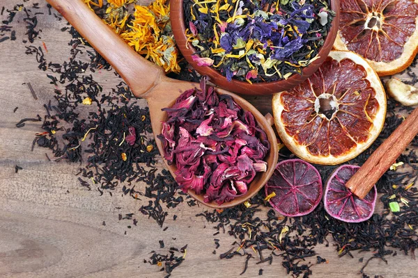 干茶的配送 木桌上的不同品种的茶 混合茶 木勺中的芙蓉和干柑橘 — 图库照片