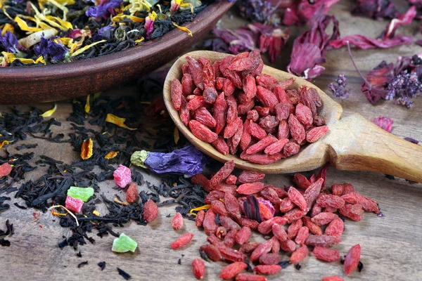 用木勺和木桌上的各种茶做山核桃浆果 混合茶与花花瓣和醋栗浆果特写 — 图库照片