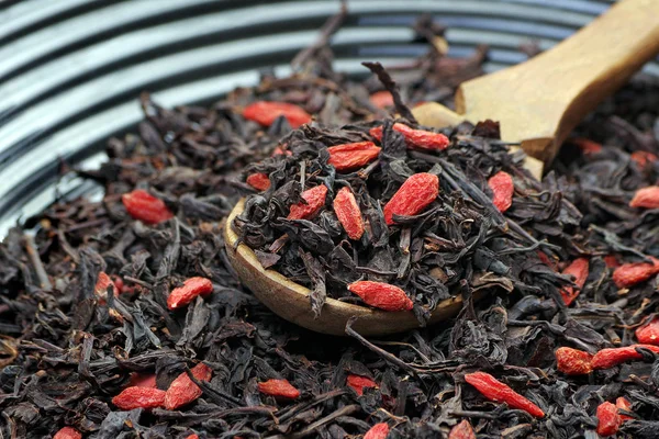 Tahta Kaşıkta Siyah Çay Yaprakları Goji Üzümleri Siyah Karıştırılmış Çay — Stok fotoğraf