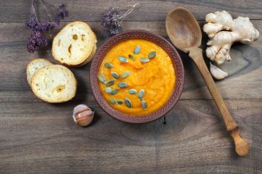 Kabak çorbası tost, kabak tohumu, zencefil ve sarımsak ahşap bir masada. sebze vitamin çorbası. en üstteki görünüm