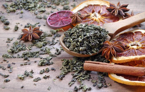 绿茶的叶子在木勺里 干柑橘 肉桂和茴香 茶和香料 — 图库照片