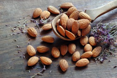 Tahta bir masada, tahta bir kaşıkta badem. Badem ve kekik. en üstteki görünüm