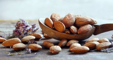 Tahta bir masada, tahta bir kaşıkta badem. Badem ve kekik. en üstteki görünüm