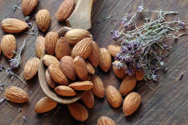 Tahta bir masada, tahta bir kaşıkta badem. Badem ve kekik. en üstteki görünüm