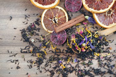 Karışık çay. Kuru çiçek yaprakları ve narenciye meyveli siyah çay. Tahta kaşıkta kuru siyah çay yaprakları. Kapat.