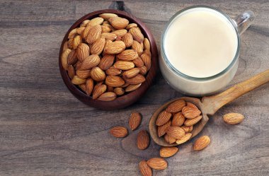 Bardakta badem sütü ve ahşap masada badem fıstığı. Üst Manzara. Boşluğu kopyala