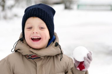 Kartopu oynayan çocuk. Elinde kartopu olan bir çocuk. Kar yiyen çocuk. Çocukların kış oyunları. Boşlukları kopyala