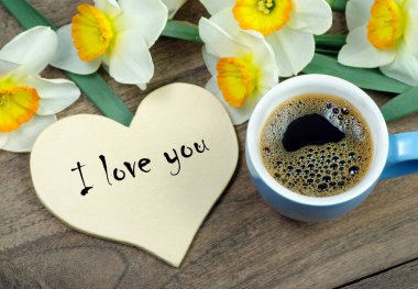 Buket ve bir fincan kahve. Narcissus ve bir fincan kahve. Kahve ve bir not. Seni seviyorum. Yazıt. Seni seviyorum. en üstteki görünüm. 
