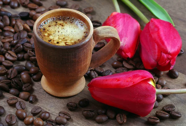 cup of coffee and red tulips on a wooden table. spring flowers and coffee
