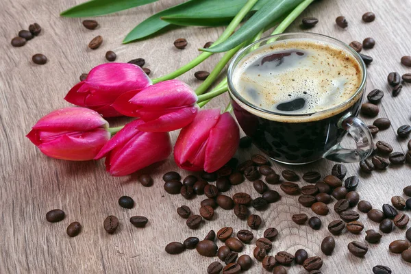 cup of coffee and a bouquet of tulips on a wooden table. close up