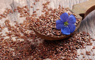 Tahta kaşıkta keten tohumu. keten çiçeği ve kuru tohumlar yakın plan.