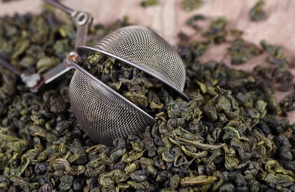 green tea leaves in a tea strainer on a table. close up. top view