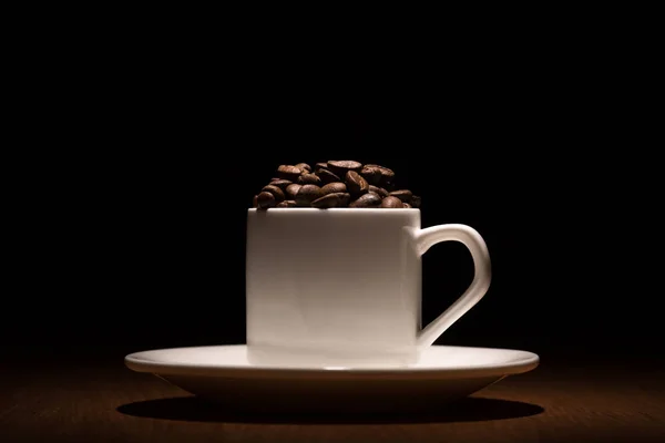 Beyaz fincan kahve kahve çekirdekleri ile tahıl Studio'da üzerinde ateş