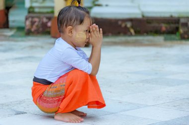 Shwedagon Pagoda, Yangon, Myanmar - 21 Ekim 2017: onun tokalar gibi küçük bir Birmanya çocuk aşağı diz çöker palms ve Lord Buddha için dua ediyor.
