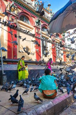 Yangon, Myanmar - 21 Ekim, 2017: Hint yoldan geçen aile güvercinler yüzlerce tarafından çevrili. İki sokak satıcıları güvercin gıda satmak için bekliyor.