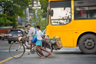 China Town, Yangon - 21 Ekim 2017: Bir üç tekerlekli bisiklet taksi şoförü dikkatle bir sepet muz ve meşgul bir kavşak ile bir yolcu dolu dolu onun üç tekerlekli bisiklet iter.