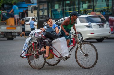China Town, Yangon 21 Ekim 2017: bir yolcu ve onun birçok plastik torba dolu merchandises, bazı onun kucağına, diğerleri kullanılabilir alan üzerinde taşıyan bir üç tekerlekli bisiklet taksi. Sürücü onları kadar nazik sokak yamaç önemsiz. 