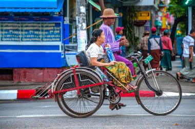 Yangon - 21 Ekim 2017: süre onlar durdurmak için yeşil trafik ışığı beklemek bir üç tekerlekli bisiklet sürücüsü onun yolcu ile samimi bir tartışma yaşıyor. . Bir üç tekerlekli bisiklet commuting genellikle düşük gelirli Birmanya tarafından kullanılır.