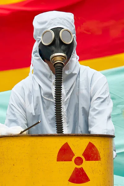 一个穿着生物危险套装和防毒面具的人 一名男子在生物危险西装站在一个生锈的坦克与核标志筛选 他戴着带有弹性橡胶呼吸管的防毒面具 — 图库矢量图片