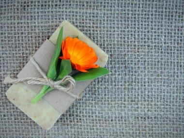 Çuval bezi zemin üzerine calendula çiçek olan el yapımı doğal sabun çubuk.