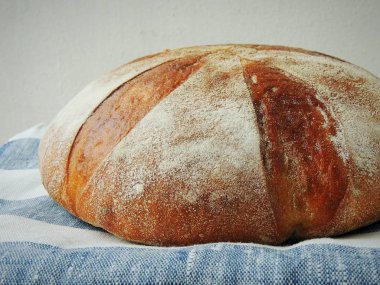 Taze somun ekmek el yapımı çizgili beyaz mavi keten havlu üzerinde.