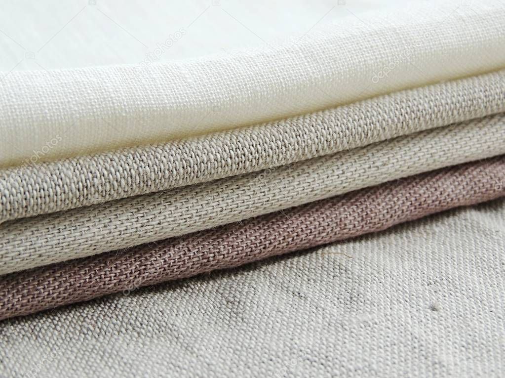 Pile of handmade dull-colored waffle linen cotton napkins towels on white linen background. Different colors. Food photo props. Natural waffle linen cotton fabric. 