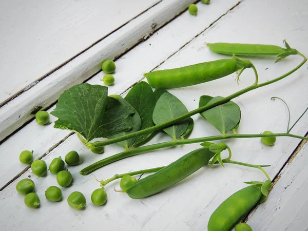 Organic natural sweet green peas, peas in pods on vintage wooden white background.