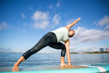 Sup Yoga pratik yan bend atletik genç kadın poz Ala içinde 