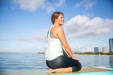 Sup Yoga pratik onun kürek üzerinde rahatlatıcı atletik genç kadın
