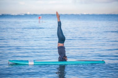 Güneşli sabah antrenmanın Sup Yoga Pratik kullanımda oldukça genç bir kadın