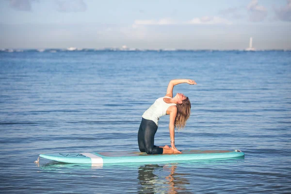 Zonnige ochtend werk uit een mooie jonge vrouw in Sup Yoga terug ben — Stockfoto
