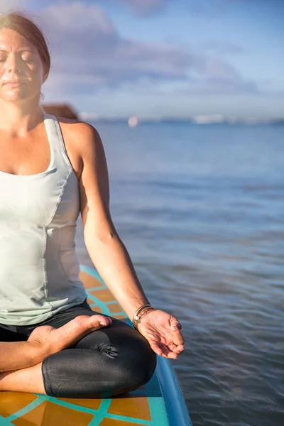 Обрезанная фотография женщины в медитации после ее SUP йоги на — стоковое фото