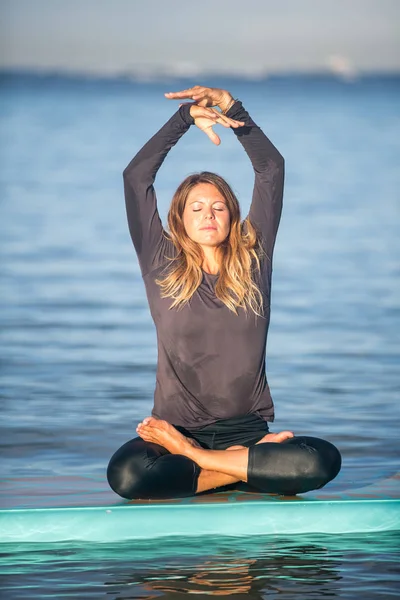 Mooie vrouw in meditatie na haar Sup Yoga op het water — Stockfoto