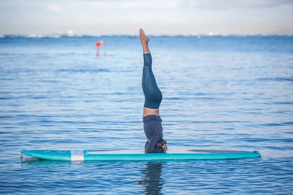 Солнечным утром тренируйтесь с симпатичной молодой женщиной на тренировке SUP Yoga — стоковое фото