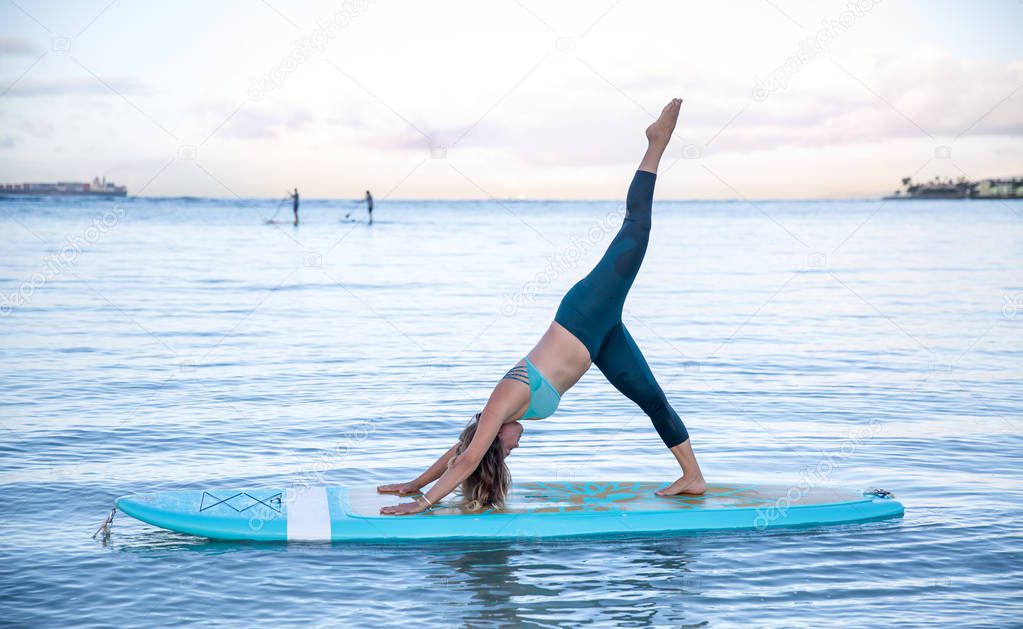 Athletic young woman in SUP Yoga practice side bend leg lift Pos