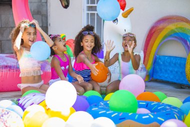Yaz havuzu partisi güneş gözlüklü tatlı kızlar balonlarla oynuyorlar.