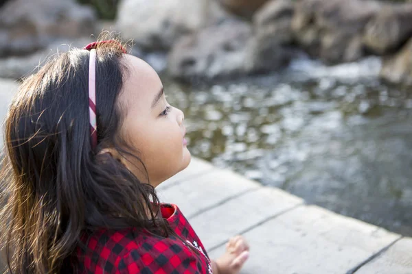 Милая маленькая девочка бросила монетку в пруд и загадывает желание. — стоковое фото