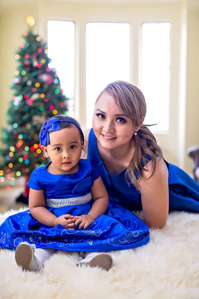 Mutter und kleine Tochter posieren für ein Weihnachtsfoto lizenzfreie Stockbilder