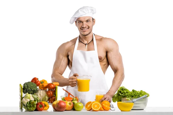 Muž kulturista cook, vaření čerstvě vymačkané džusy a zeleninové plodiny — Stock fotografie