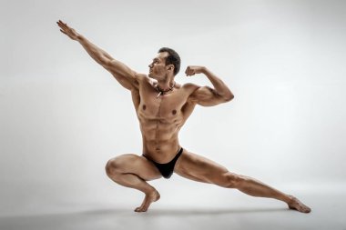 Çok kaslı atletik adam - vücut geliştirmeci, beyaz arka plan üzerinde poz