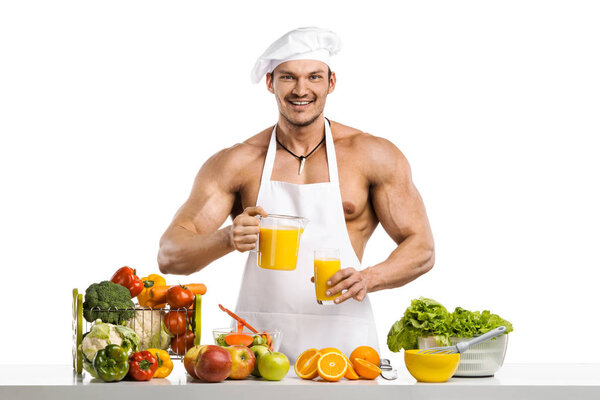 Man bodybuilder cook, cooking freshly squeezed juice and vegetab