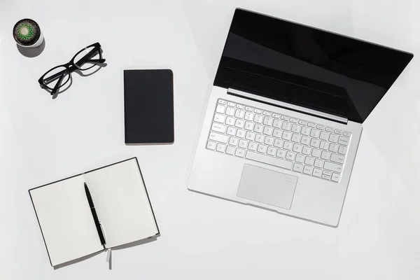Современный белый минималистичный стол с ноутбуком, ноутбук с ручкой и очками. Вид сверху с пространством для копирования. Концепция рабочего стола . — стоковое фото
