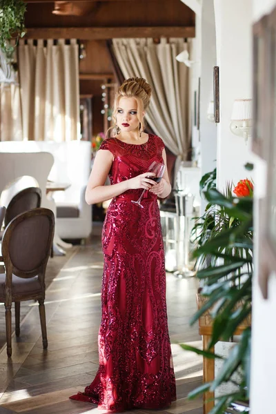 Krásná žena pózuje v červené dlouhé šaty s vlakem v luxusní interiér restaurace — Stock fotografie