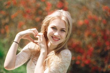 Çiçeklenme içinde çekici sarışın bahar bahçe. Kadın el kalp şeklinde Çiçek Bahçesi