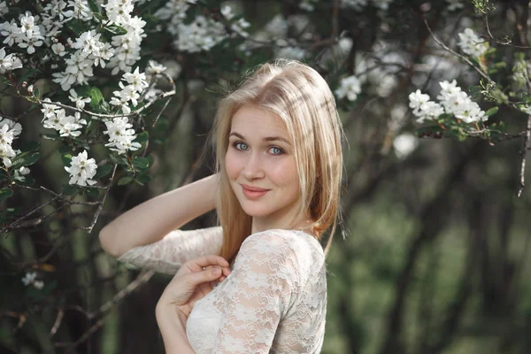 Jonge vrolijke blonde genieten van bloesem appel in de tuin. Bloeiende lente, liefde, geluk concept — Stockfoto