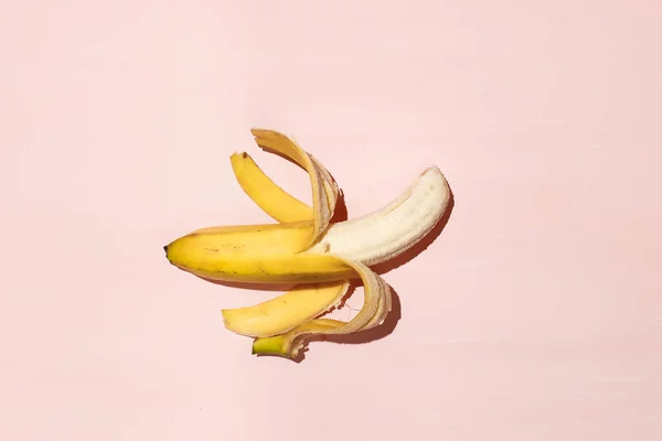 Sweet juicy opened banana on pink table. Sexual life libido and potency concept